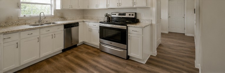 The same kitchen after cleaning and refit with white cabinetry and stainless appliances